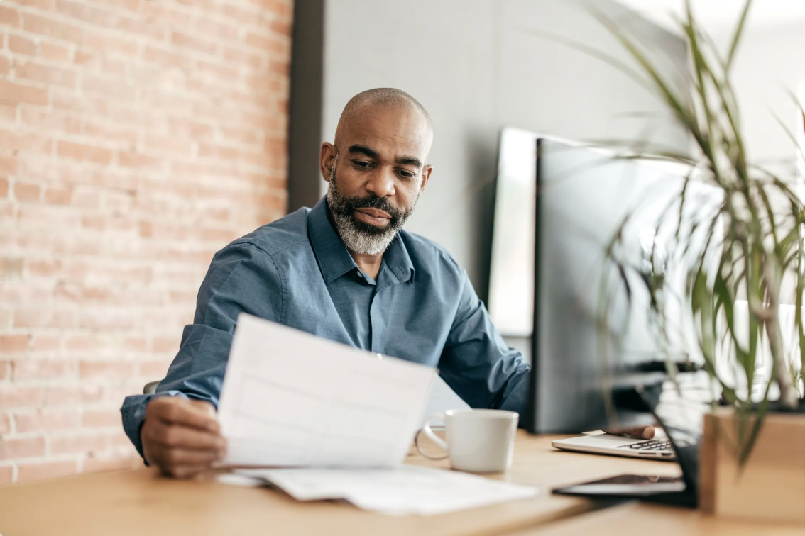 Professional employee reviewing documents and workflows at an organized office desk